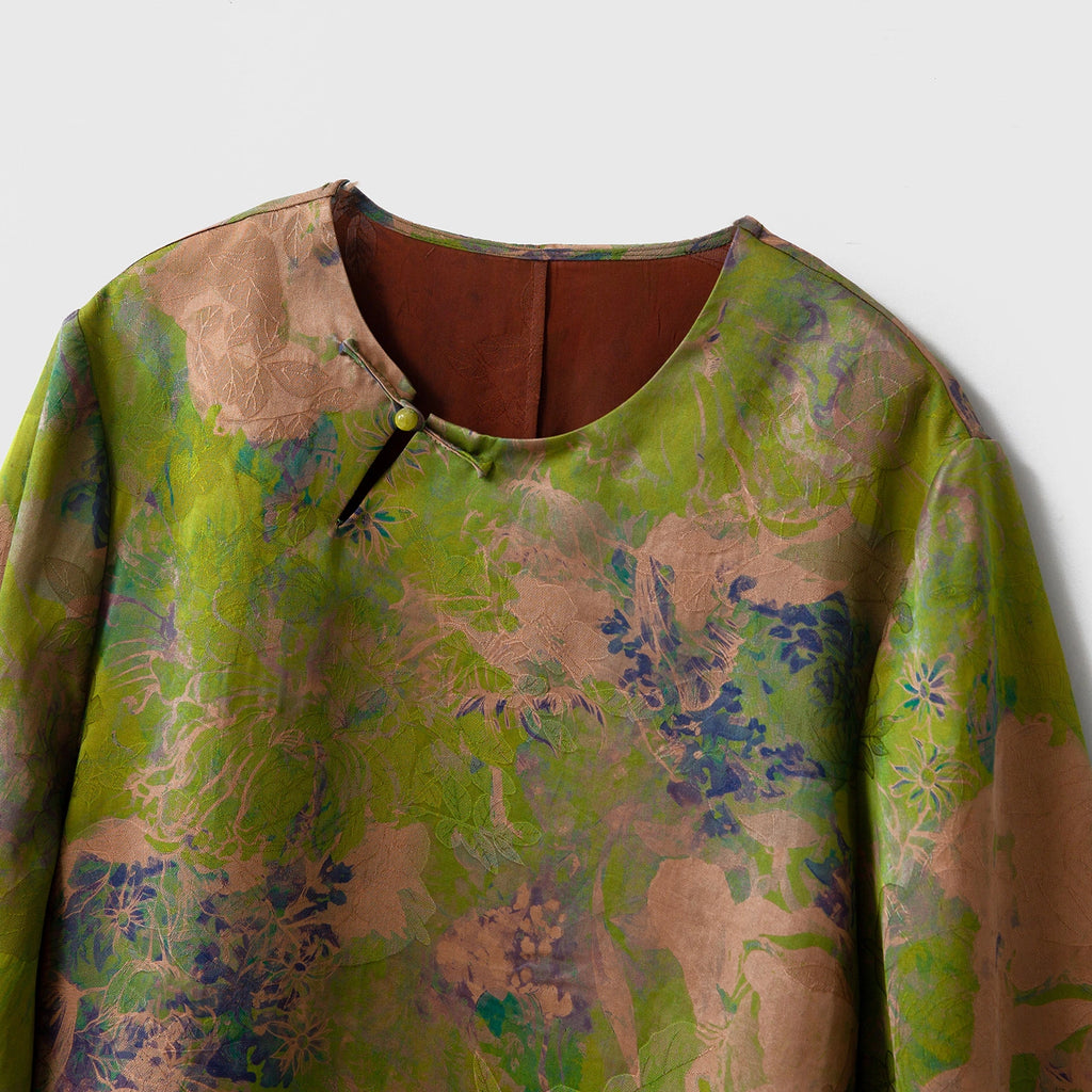 Close-up of the round neckline and asymmetric button closure on the floral Xiangyunsha silk blouse