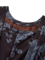 Close-up of the round neckline and back zipper of a brown Xiangyunsha silk dress, highlighting the intricate blue floral jacquard texture and the contrast brown lining.