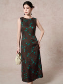 Front view of a dark brown mulberry silk dress with a round neckline, sleeveless design, and elegant green floral jacquard pattern, styled with a cream handbag.