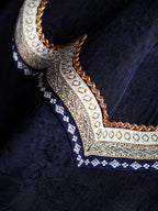 Close-up of the layered geometric neckline embroidery on midnight navy Xiangyunsha silk fabric