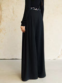 Side view of Yangui black pants showing the embroidered velvet waistband and flowing wide legs.