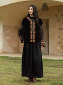 Black silk and shearling jacket with embroidered borders, paired with flowing black wide-leg trousers