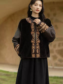 Close view of the jacket showing its embroidered neckline and cuffs, metal clasp, and contrasting silk and shearling textures