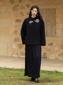 Full-length front view of the Yanshuang black wool coat with silver-tone floral embroidery, styled with a long black skirt