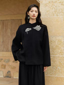 Three-quarter view of the Yanshuang black wool coat, showing its relaxed silhouette and metallic floral embroidery