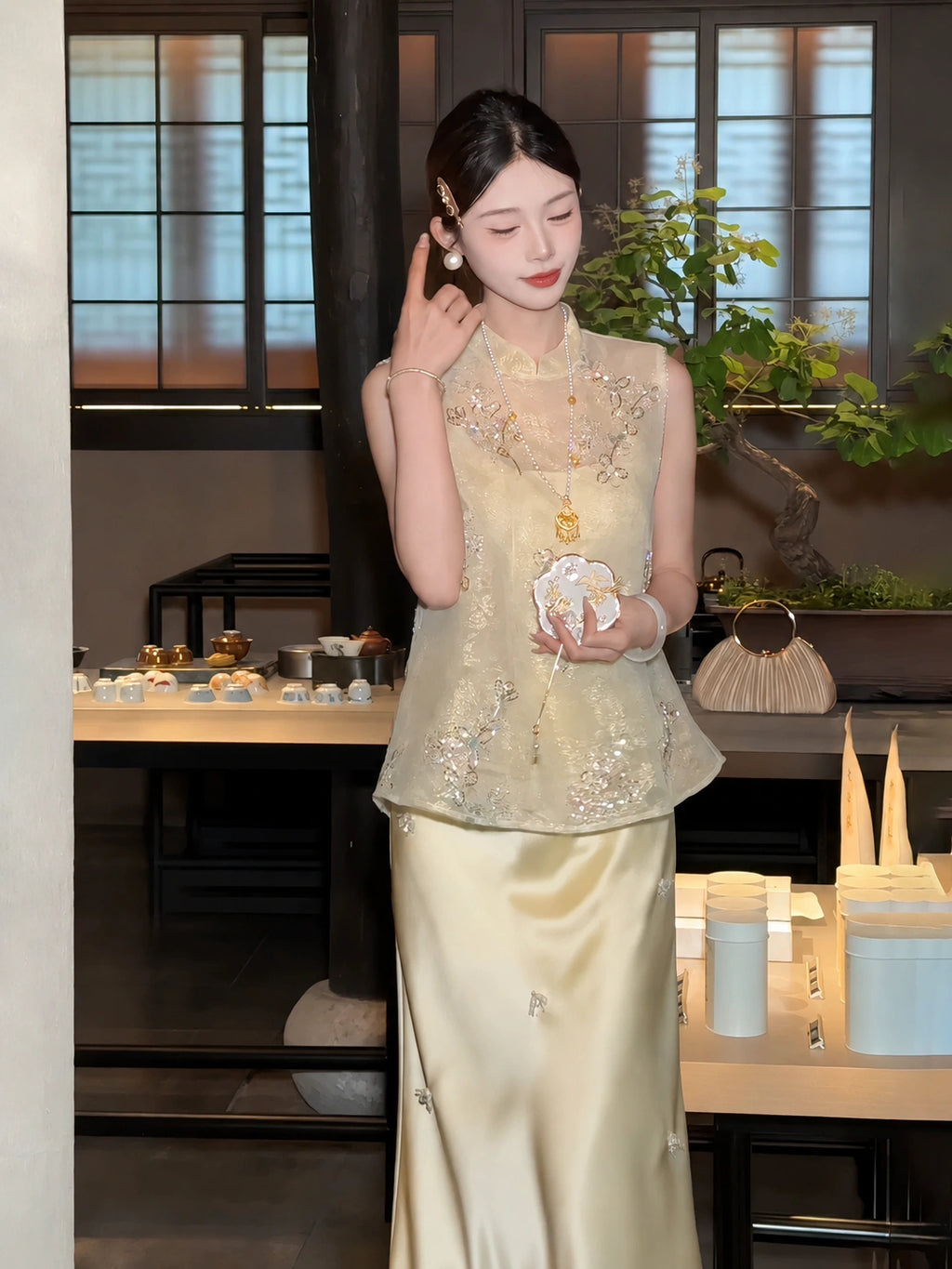Side view of a yellow sleeveless embroidered vest with sequin details, holding a fan, highlighting the intricate beadwork and relaxed fit.