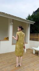 Back view of a yellow Cheongsam midi dress with sleeveless design and mandarin collar, featuring a textured jacquard fabric, paired with white heels.