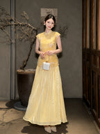 Full body shot of a yellow Cheongsam dress with floral embroidery and pleated skirt, styled with a white bag and pearl shoes, crafted from 100% polyester.