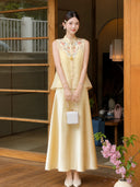 Model in a yellow Cheongsam vest with embroidered yoke and A-line satin skirt, holding a white handbag, showcasing the elegant 100% polyester fabric.