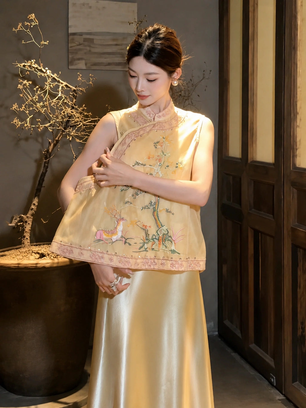 Model wearing a yellow embroidered Cheongsam vest with a mandarin collar and deer motif, paired with a yellow satin skirt, showcasing the 100% polyester fabric.