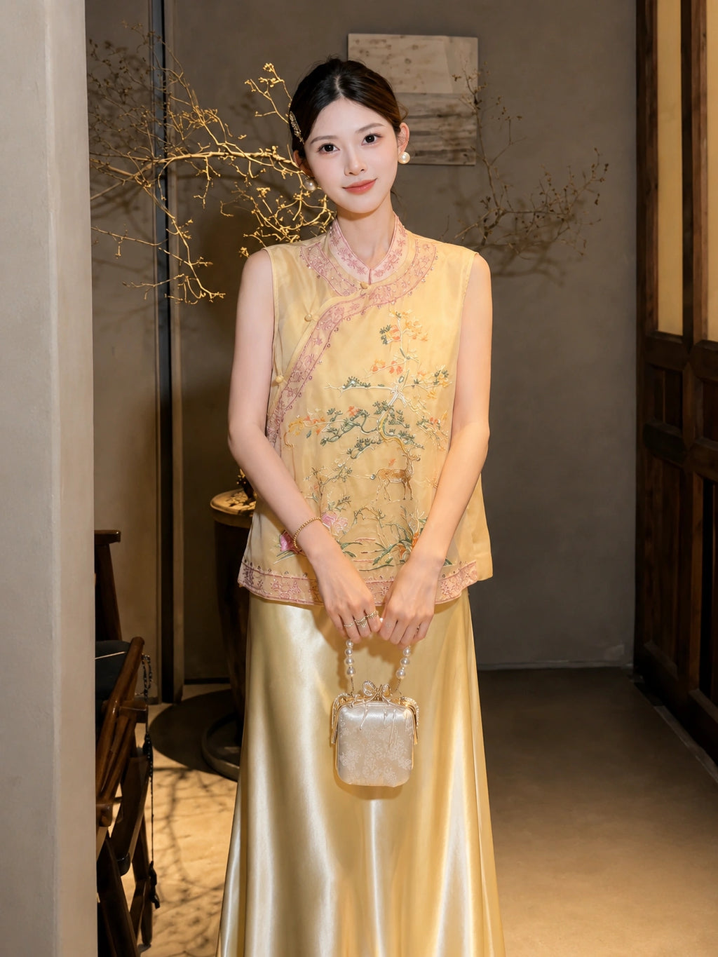 Model in a yellow sleeveless embroidered vest with a mandarin collar, holding a handbag, highlighting the intricate embroidery and elegant silhouette.