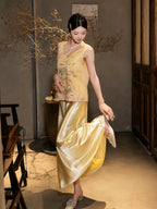 Model lifting the hem of a yellow satin skirt while wearing a yellow embroidered vest, highlighting the layered styling and the rich embroidery on the vest.