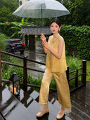 Front view of a yellow sleeveless Cheongsam vest with scalloped lace hem, styled with matching pants, standing on a wooden deck, crafted from a breathable Viscose-Polyester blend.
