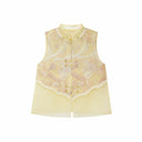Flat lay of a yellow sleeveless vest with gold metallic buttons, lace trim, and a layered sheer hem, crafted from a Lyocell-metallic blend.