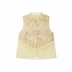 Flat lay of a yellow sleeveless vest with gold metallic buttons, lace trim, and a layered sheer hem, crafted from a Lyocell-metallic blend.