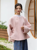 Front detail of the Yuyan coat showing its blush pink mélange texture, asymmetric front, and side buttons