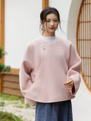 Front view of the blush pink wool coat showing side button details, wide sleeves, and a rounded hem